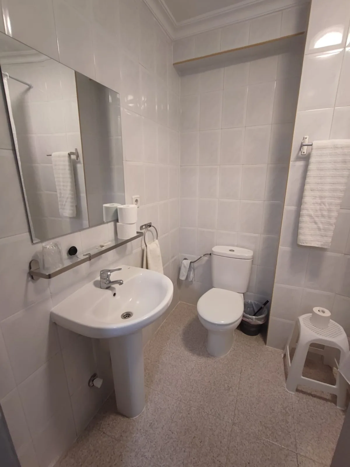 Baño completo con lavabo, espejo y toallas blancas