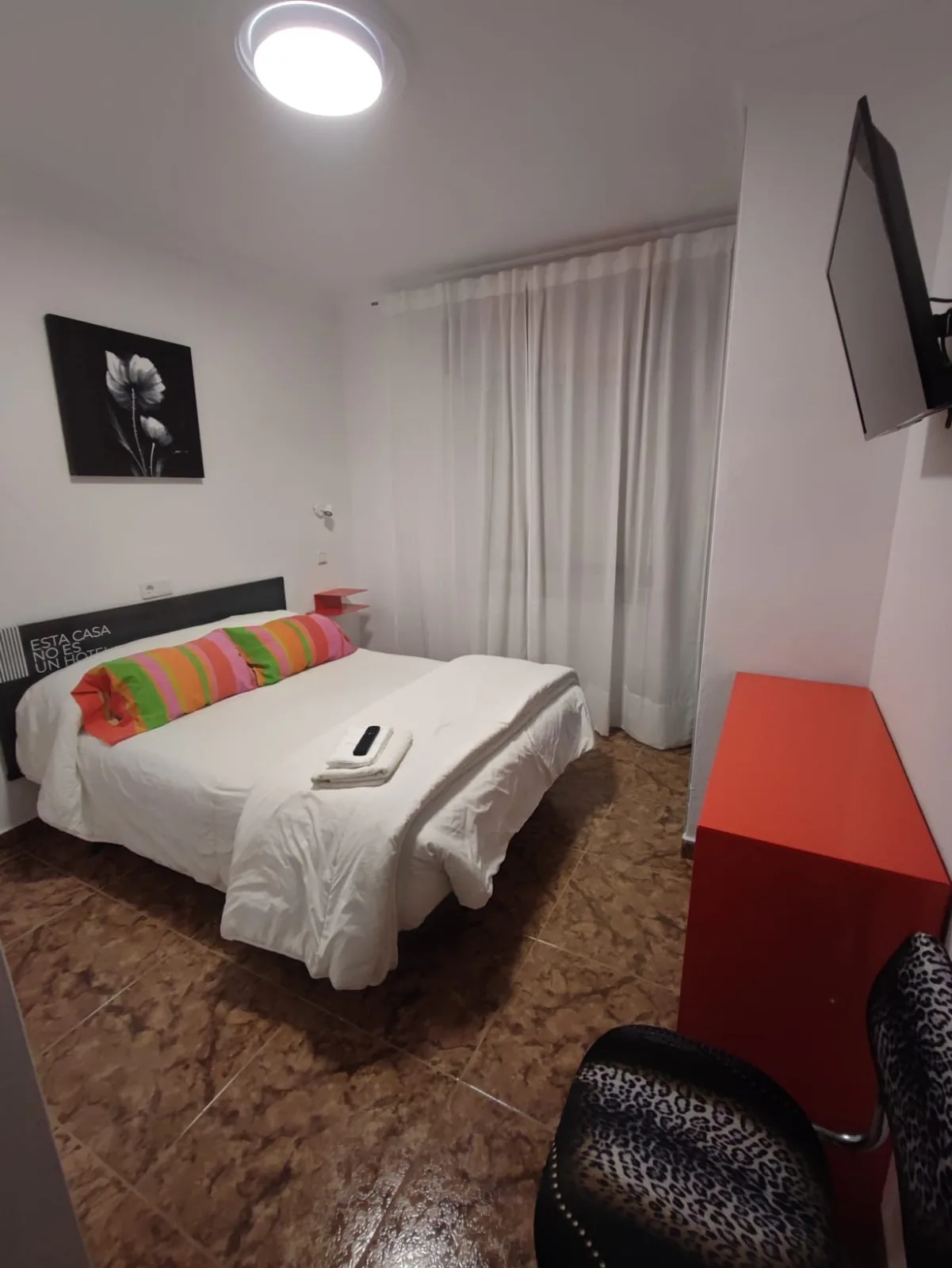 Habitación con cama doble, cuadro decorativo y televisor